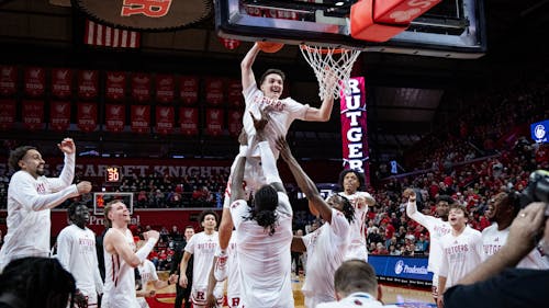 The Rutgers men's basketball team is all smiles as it lifts senior guard Aiden Terry for a slam dunk as part of a pregame ritual. – Photo by Christian Sanchez