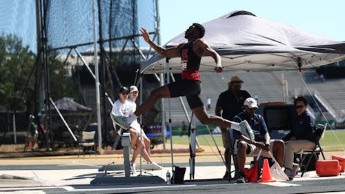 Junior sprinter and jumper Sincere Robinson leaps over a hurdle in the South Florida Invitational. – Photo by Chris Henry / scarletknights.com