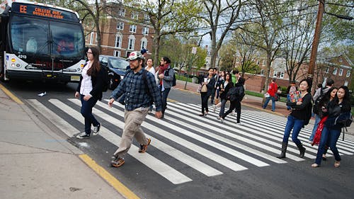 A bus stops for students as they cross College Avenue. Vehicles are legally obligated to stop for pedestrians in a marked crosswalk. – Photo by Nelson Morales
